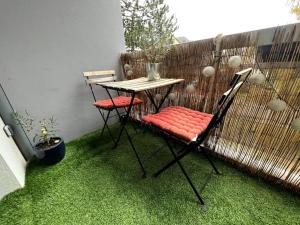a table and two chairs on a patio with grass at Joli appartement à Fegersheim in Fegersheim
