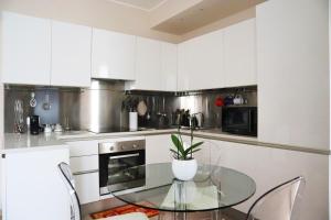 a kitchen with white cabinets and a glass table at Repubblica Elegant Milan House in Milan