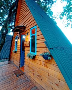 a cabin with a blue door on a wooden deck at Chalés Recanto do Vale - GRALHA AZUL in Bom Jardim da Serra