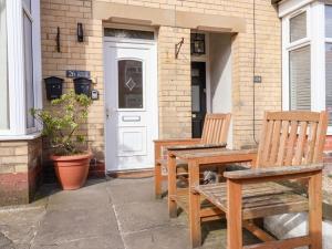 due panche di legno sedute fuori da una casa con una porta di Lucys Retreat a Bridlington