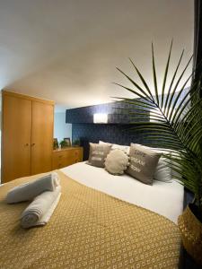 een slaapkamer met een bed met kussens en een plant bij Modern Studios Close To Hyde Park in Londen