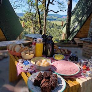 uma mesa coberta com pratos de comida numa mesa em Chalés Recanto do Vale - GRALHA AZUL em Bom Jardim da Serra