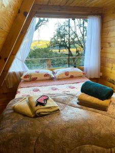 ein großes Bett in einem Zimmer mit Fenster in der Unterkunft Chalés Recanto do Vale - GRALHA AZUL in Bom Jardim da Serra