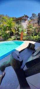 una piscina con una estatua frente a una casa en Solar da Suzi en Praia do Rosa