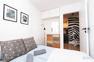 a white bedroom with a bed and a mirror at Baltic Breeze Apartment 3city Gdańsk by Noclegi Renters in Gdańsk