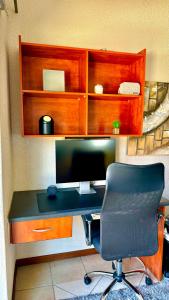 a desk with a computer monitor and a chair at Chic Urban Loft in Pretoria in Pretoria