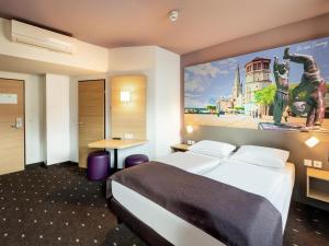 una habitación de hotel con una cama y un cuadro en la pared en B&B HOTEL Düsseldorf-Mitte, en Düsseldorf