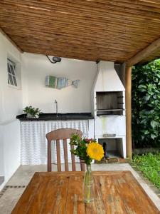 a vase of flowers on a wooden table with a stove at Casinha Pescador in Paraty
