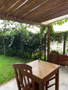 a wooden table and two chairs under a wooden pergola at Casinha Pescador in Paraty