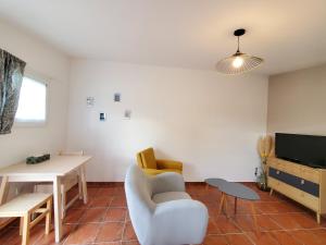 sala de estar con sofá, mesa y TV en Le Bleu Mimosa, en Narbona