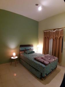 ein Schlafzimmer mit einem Bett und einem Tisch mit einer Lampe in der Unterkunft Manyak Villa at Berastagi Resort C14 Jl Mimpin Tua in Berastagi