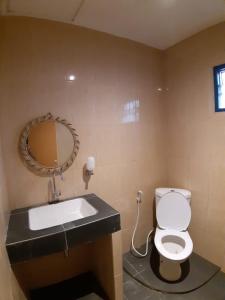 La salle de bains est pourvue d'un lavabo, de toilettes et d'un miroir. dans l'établissement Manyak Villa at Berastagi Resort C14 Jl Mimpin Tua, à Berastagi