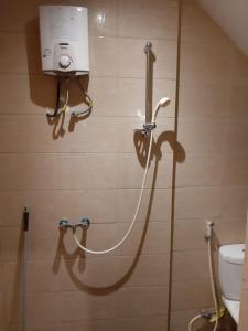 La salle de bains est pourvue d'une douche et d'un tuyau sur le mur. dans l'établissement Manyak Villa at Berastagi Resort C14 Jl Mimpin Tua, à Berastagi