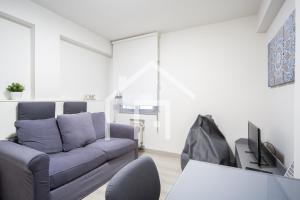 uma sala de estar com um sofá e uma televisão em Ático Quintana II - con terraza, en el centro con Wifi y garaje em Oviedo