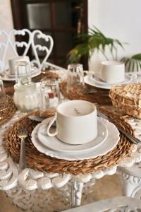 une table avec des assiettes et des tasses blanches et de la vaisselle dans l'établissement Peixe Crew Centro, à Búzios