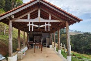 a large wooden pavilion with a table and chairs at Sitio Cachoeira da Gomeira in Passa Quatro