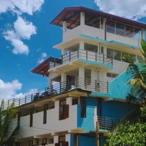 a white and blue building with a balcony at Ran Dhara Beach Resort in Ambalangoda