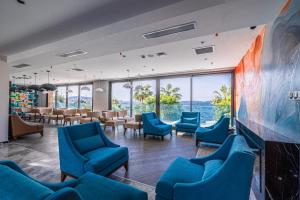 a waiting room with blue chairs and a large wall of windows at Gözegir Hotel in Bodrum City
