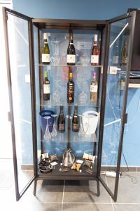 une armoire en verre remplie de bouteilles de vin et de verres dans l'établissement Le Domaine de la Clarté AUXERRE - VENOY, à Auxerre