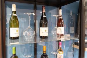 a display case with wine bottles and wine glasses at Le Domaine de la Clarté AUXERRE - VENOY in Auxerre