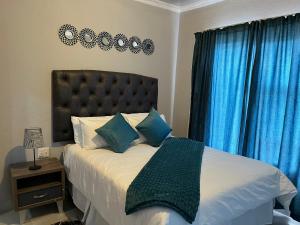 a bedroom with a large bed with blue curtains at Mafikeng Boutique Lodge in Mahikeng