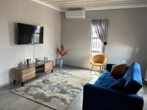 a living room with a blue couch and a tv at Mafikeng Boutique Lodge in Mahikeng