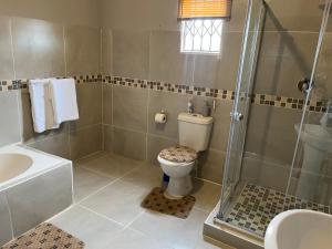 a bathroom with a shower and a toilet and a sink at Mafikeng Boutique Lodge in Mahikeng