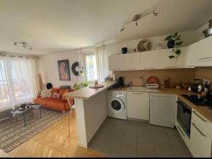 a kitchen with white cabinets and an orange couch at La Belle Échappée à Montreuil in Montreuil