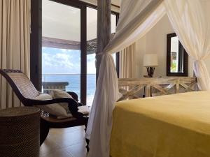 a bedroom with a bed and a view of the ocean at Chalets Bougainville in Takamaka +70 photos