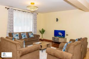 a living room with couches and a flat screen tv at Taliah Homestays in Nanyuki