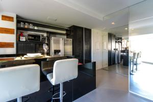 a kitchen with black cabinets and white bar stools at Çiragan Apartments by BnbHost in Sao Paulo