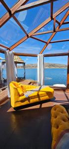 un canapé jaune assis sur le pont d'un bateau dans l'établissement Glamping Titicaca Perú, à Puno