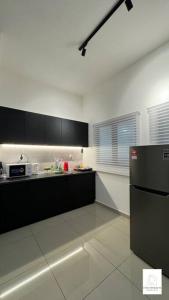 eine Küche mit schwarzen Schränken und einem Kühlschrank in der Unterkunft Hot & Wild Couple Room@Cheras KL in Cheras