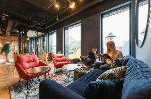 un groupe de personnes assises dans une pièce avec des canapés et des chaises dans l'établissement MEININGER Kraków Centrum, à Cracovie