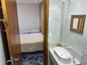 baño pequeño con lavabo y cama en Moradas Desterro, próximo ao aeroporto 02, en Florianópolis