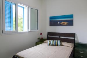 a bedroom with a bed and two windows at Villa Dafne in Villaggio Azzurro +44 photos