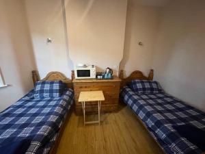 a room with two beds and a table with a microwave at Abbey Guest House in Milton Keynes
