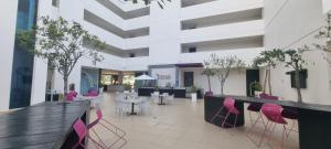 a lobby with pink chairs and tables in a building at Hermoso estudio con vista al mar en el Town Center de Playa Blanca Panamá in Playa Blanca