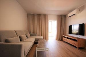 a living room with a couch and a flat screen tv at Yamato Apartment Albir in Albir
