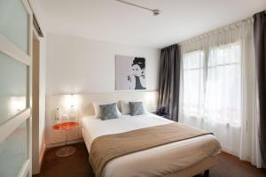 a bedroom with a bed and a window at Hôtel Miléade Les Pléïades La Baule in La Baule