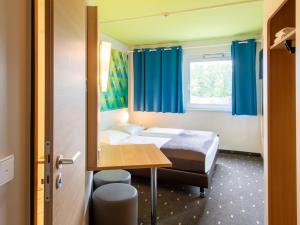 una camera con due letti e un tavolo e una finestra di B&B Hotel Erlangen a Erlangen