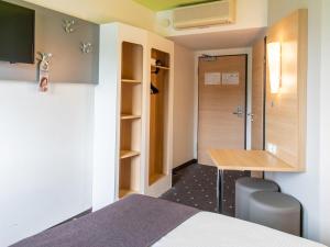 a room with a bed and a desk and a shower at B&B Hotel Erlangen in Erlangen