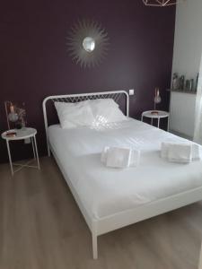 ein weißes Bett in einem Schlafzimmer mit 2 Tischen in der Unterkunft Azurea - Charmant appartement à Andernos-les-Bains in Andernos-les-Bains