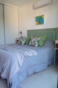 Una cama con sábanas azules y almohadas en un dormitorio en Agustín I Apart en Paraná