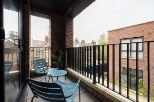einen Balkon mit Stühlen, Tischen und Fenstern in der Unterkunft The Wembley Hideout - Stylish 2BDR Flat with Balcony in London
