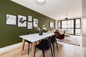 comedor con paredes verdes, mesa y sillas en The Wembley Hideout - Stylish 2BDR Flat with Balcony, en Londres