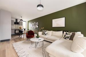 ein Wohnzimmer mit einem weißen Sofa und einer grünen Wand in der Unterkunft The Wembley Hideout - Stylish 2BDR Flat with Balcony in London