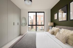 a bedroom with a white bed and a large window at The Wembley Hideout - Stylish 2BDR Flat with Balcony in London