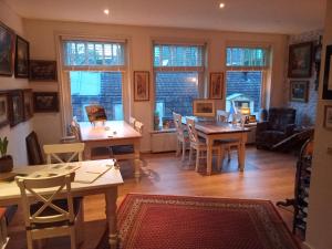 een woonkamer met tafels, stoelen en ramen bij Bed & Breakfast Moments in Schagen