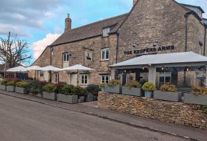 a brick building with umbrellas in front of it at The Keepers Arms in Quenington